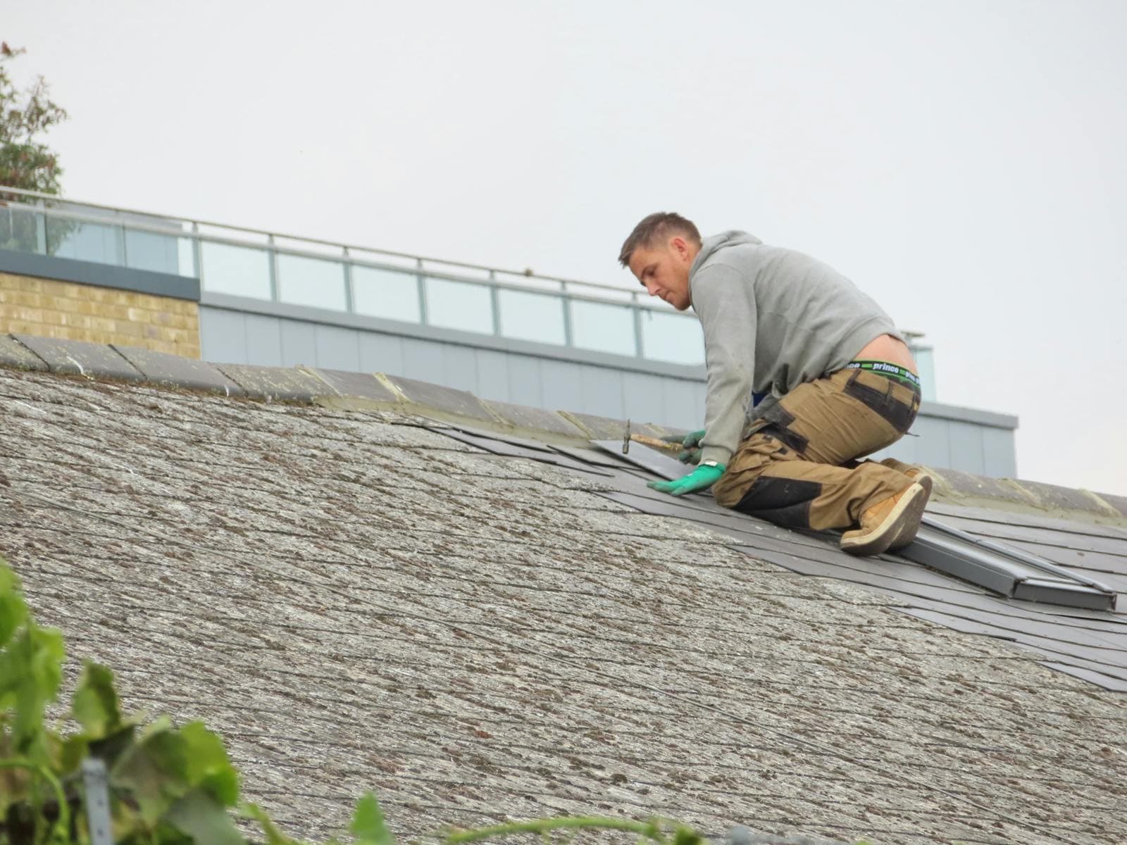 Roofer hand-nailing replacement shingles on a repair